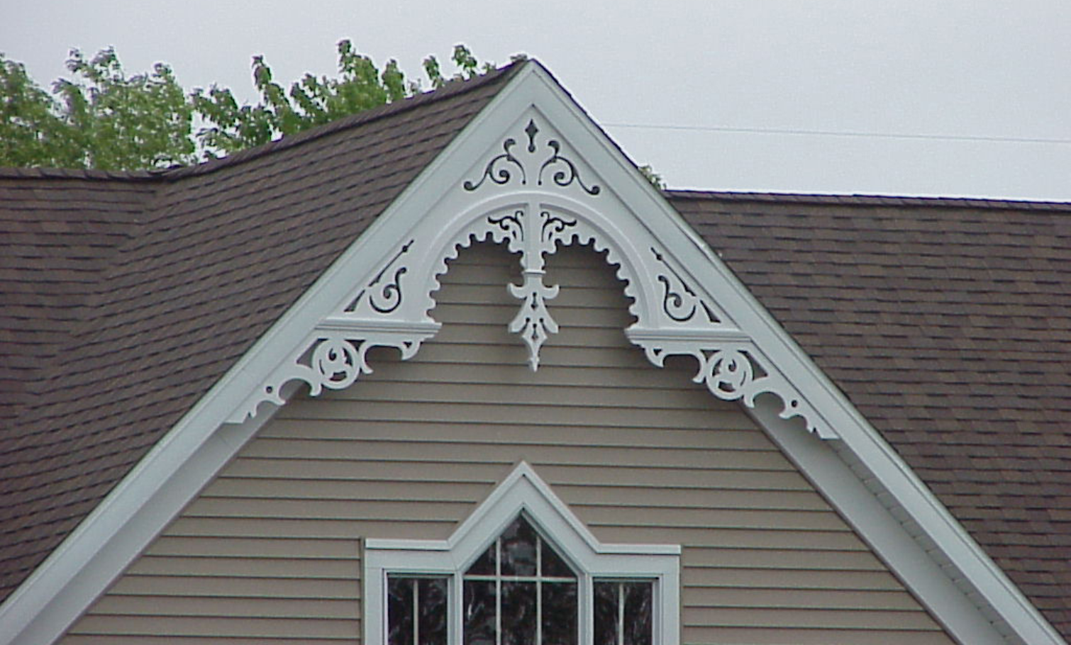 This tan-sided home has white trim and a white, Victorian-style PVC gable decoration