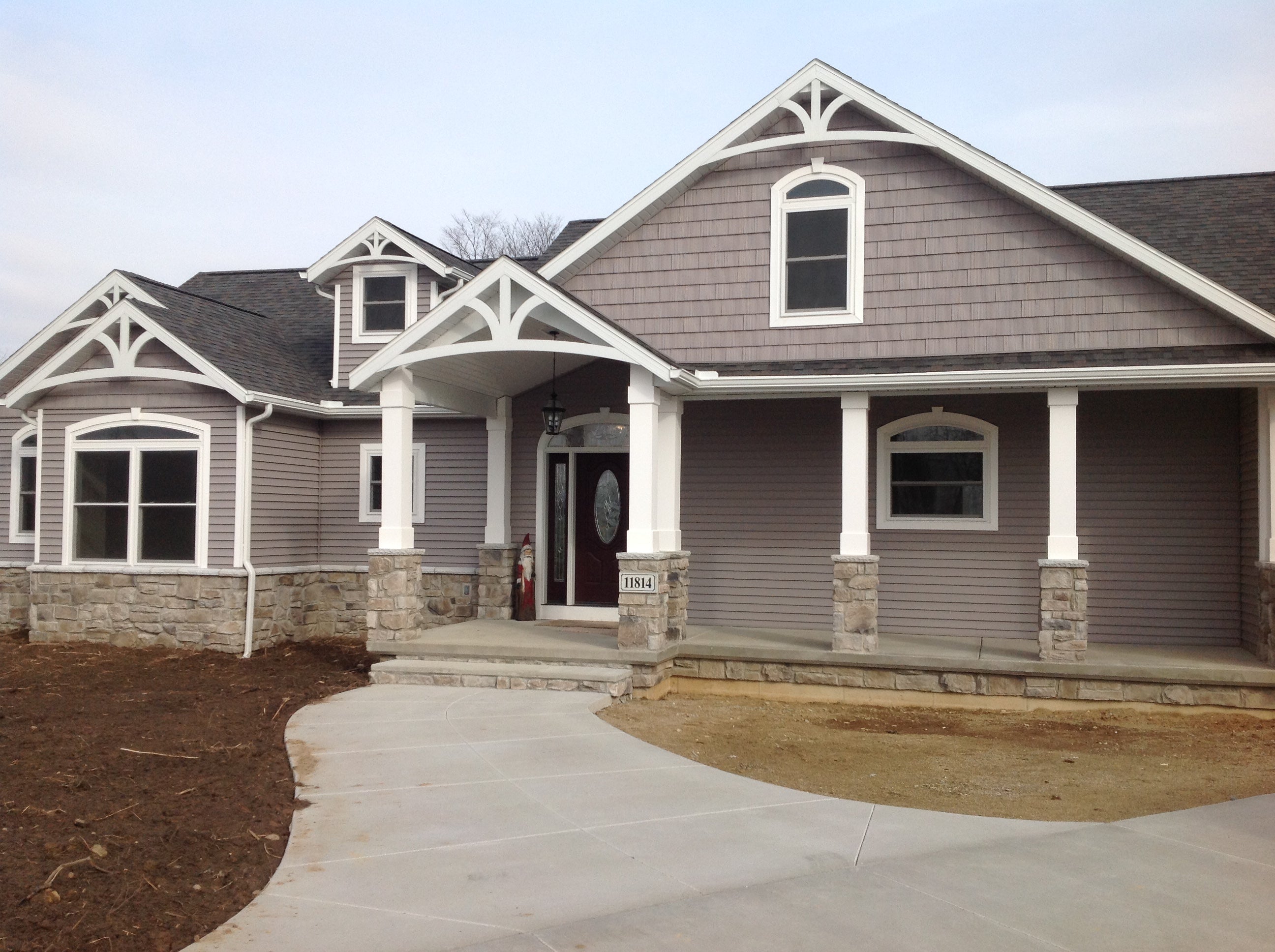 This grey home has various white gable decorations throughout the exterior design.