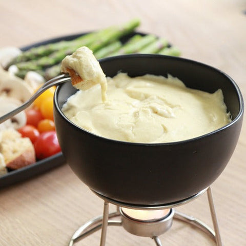 Vegan non dairy alternative fondue dip recipe in black fondue pot with bread dipping in