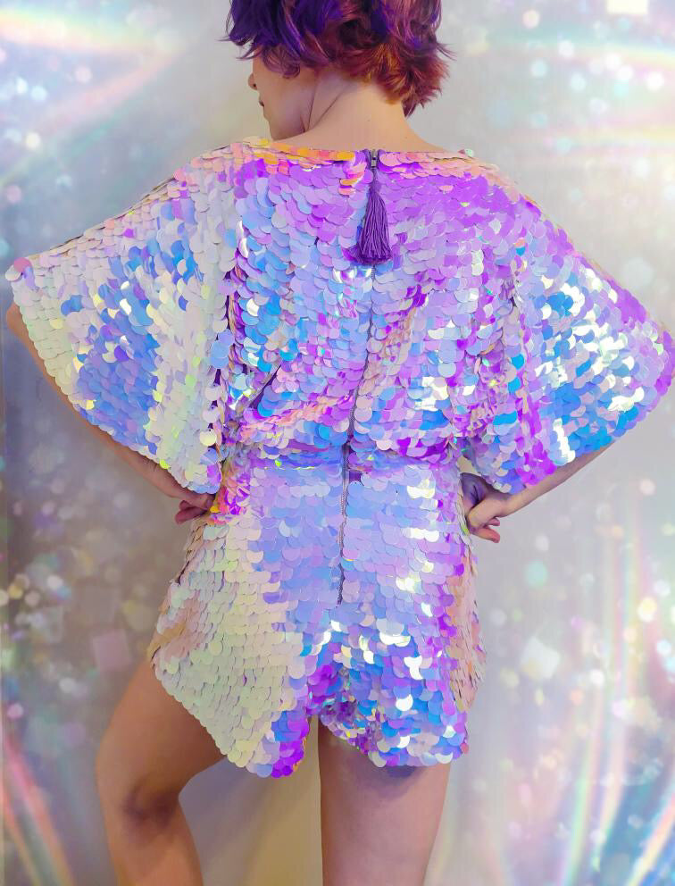 Woman with lilac hair with her back to the camera wearing an Opal coloured Rosa Bloom The Mella Sequin Playsuit