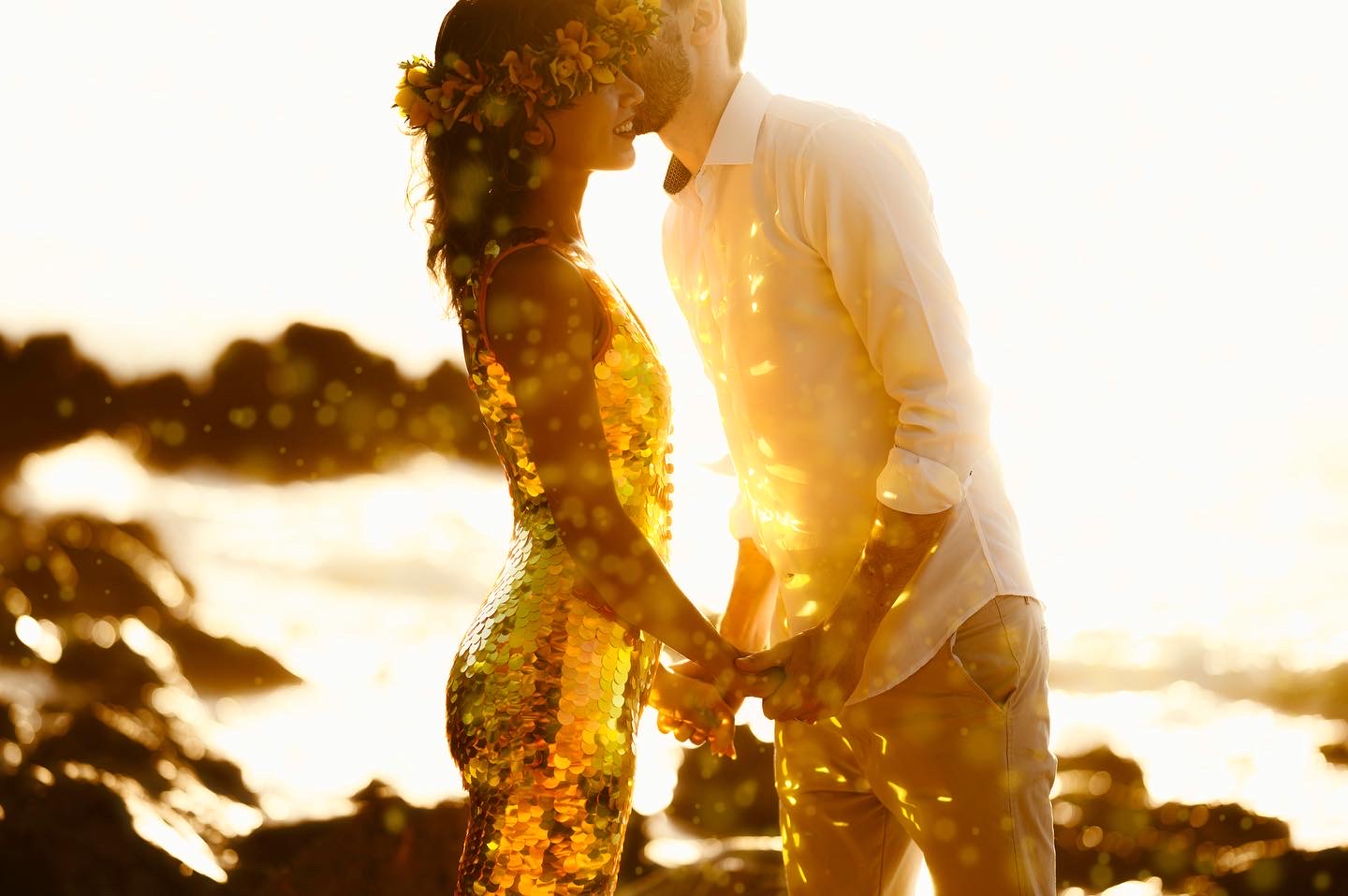 Couple kissing in golden light wearing a gold sequin jumpsuit