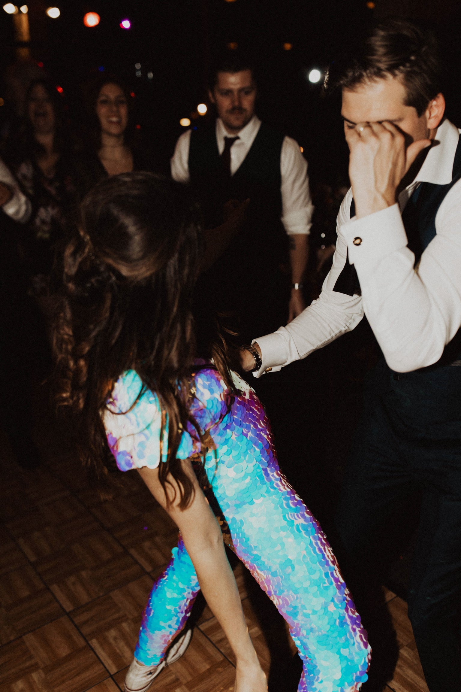 Woman in jumpsuit covered in large white sequins dances on the dancefloor