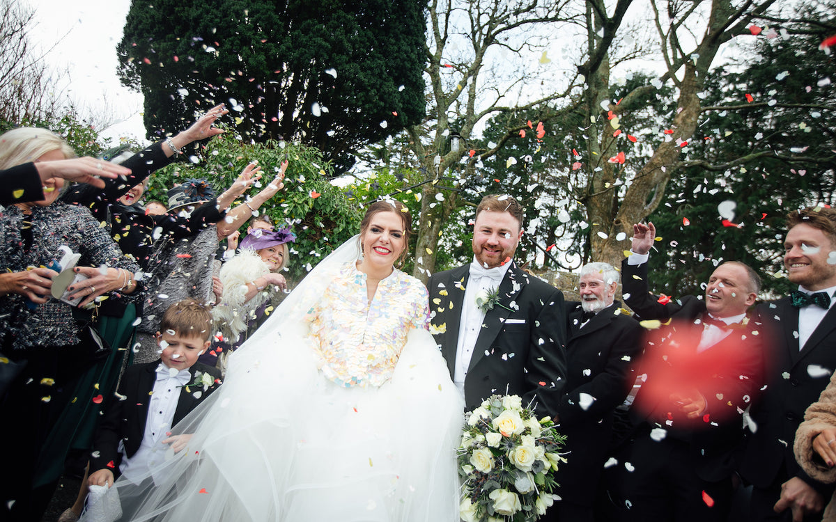 Wedding guests throw confetti over a bride and groom
