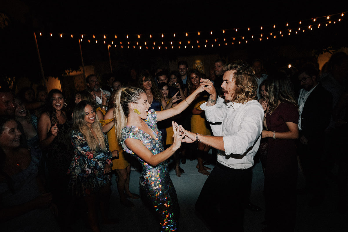 Festival style bride in a sequin jumpsuit dancing  with the groom.