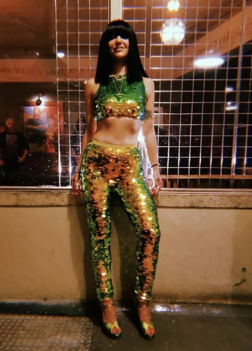 Laura Leezy posing in front of a wall wearing a Rosa Bloom Twinks Sequin Crop Top and Rosa Bloom Indus Sequin Leggings