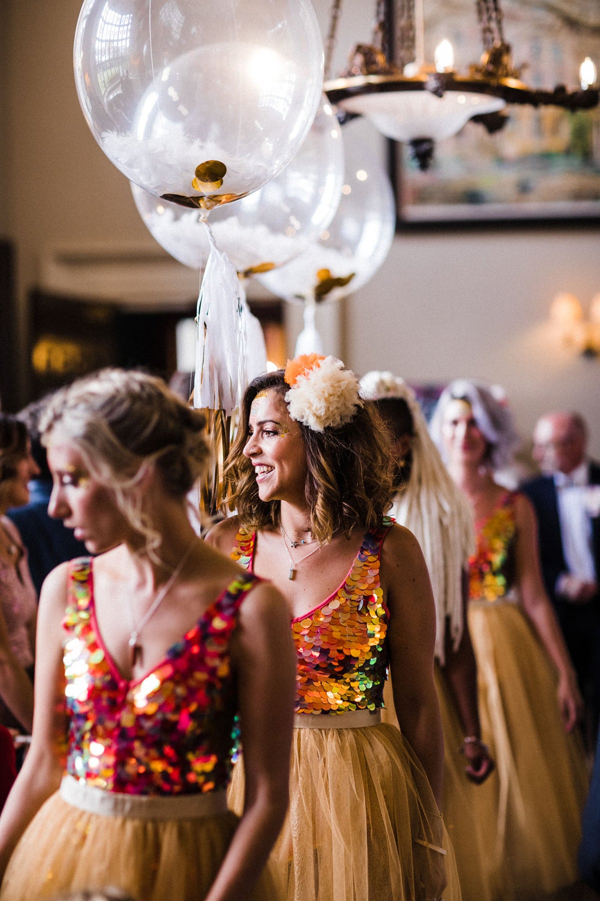 A row of bridesmaids all wearing festival style playsuits and pom-poms in their hair. 