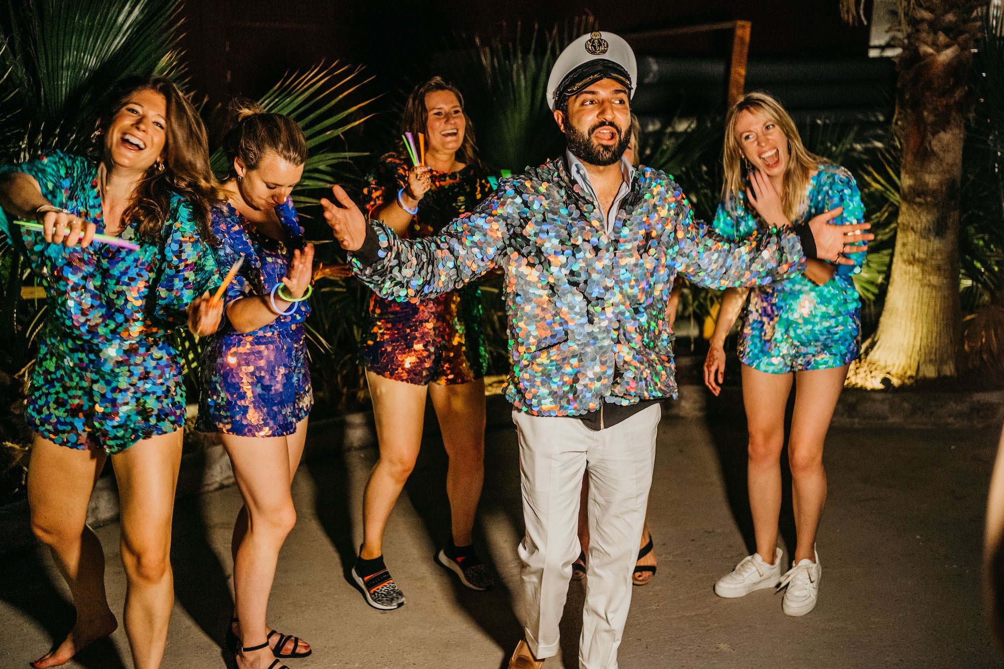 Friends in sequin outfits dance together