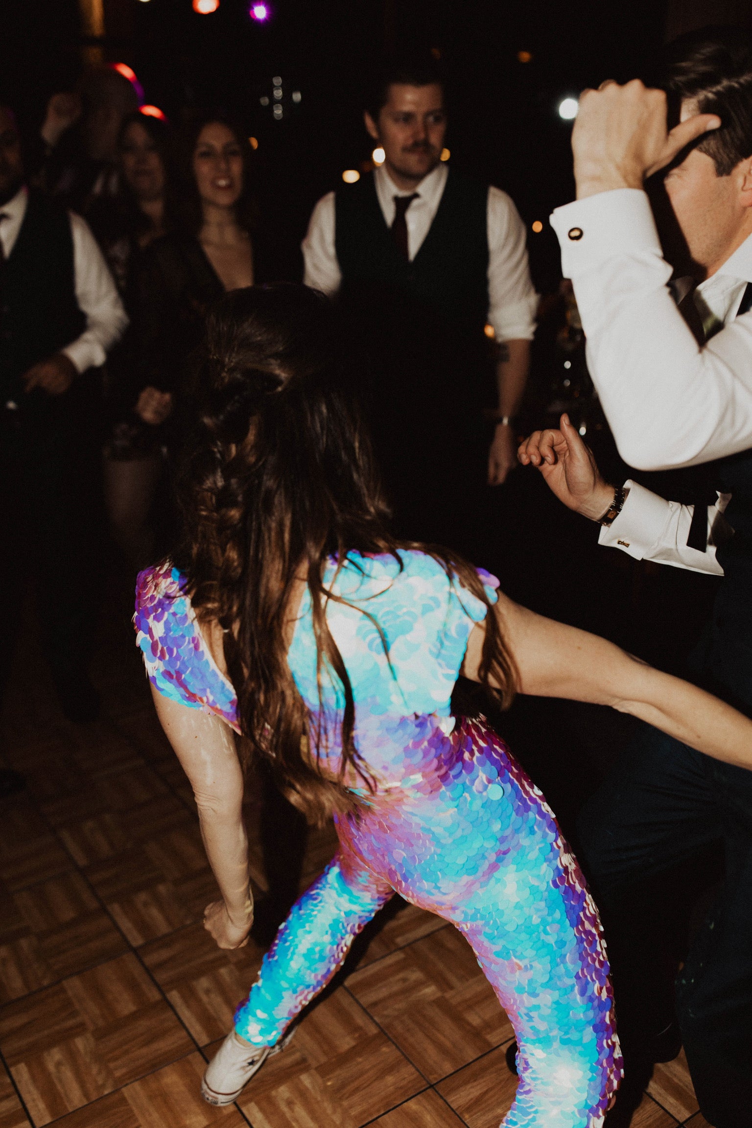 Close up image of woman in a sequin jumpsuit dancing at her wedding