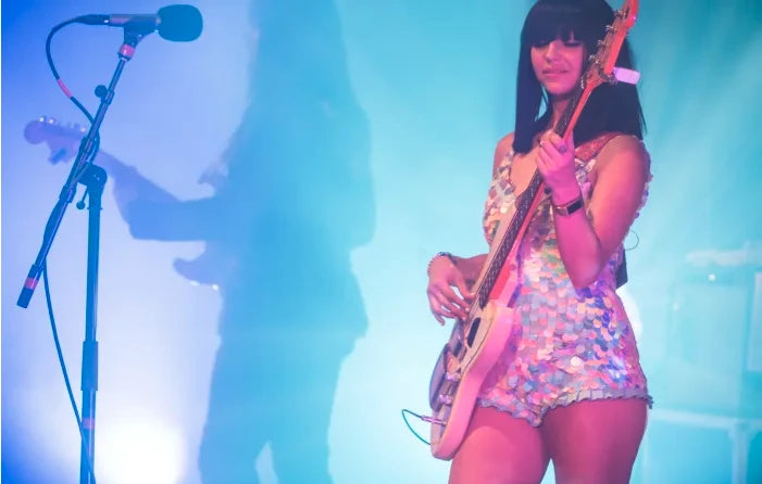 Laura Leezy playing the bass guitar on stage wearing a Rosa Bloom Sequin Sea Circus Leotard