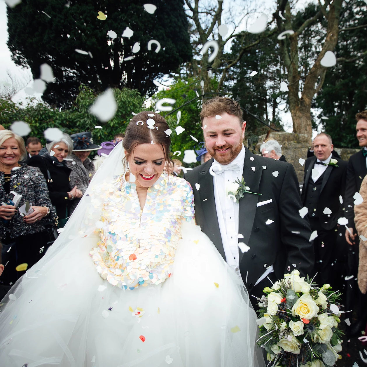 A bride wearing a sequin jacket under confetti