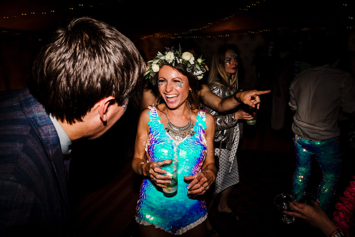 A bride wearing a festival style sequin playsuit and floral headdress