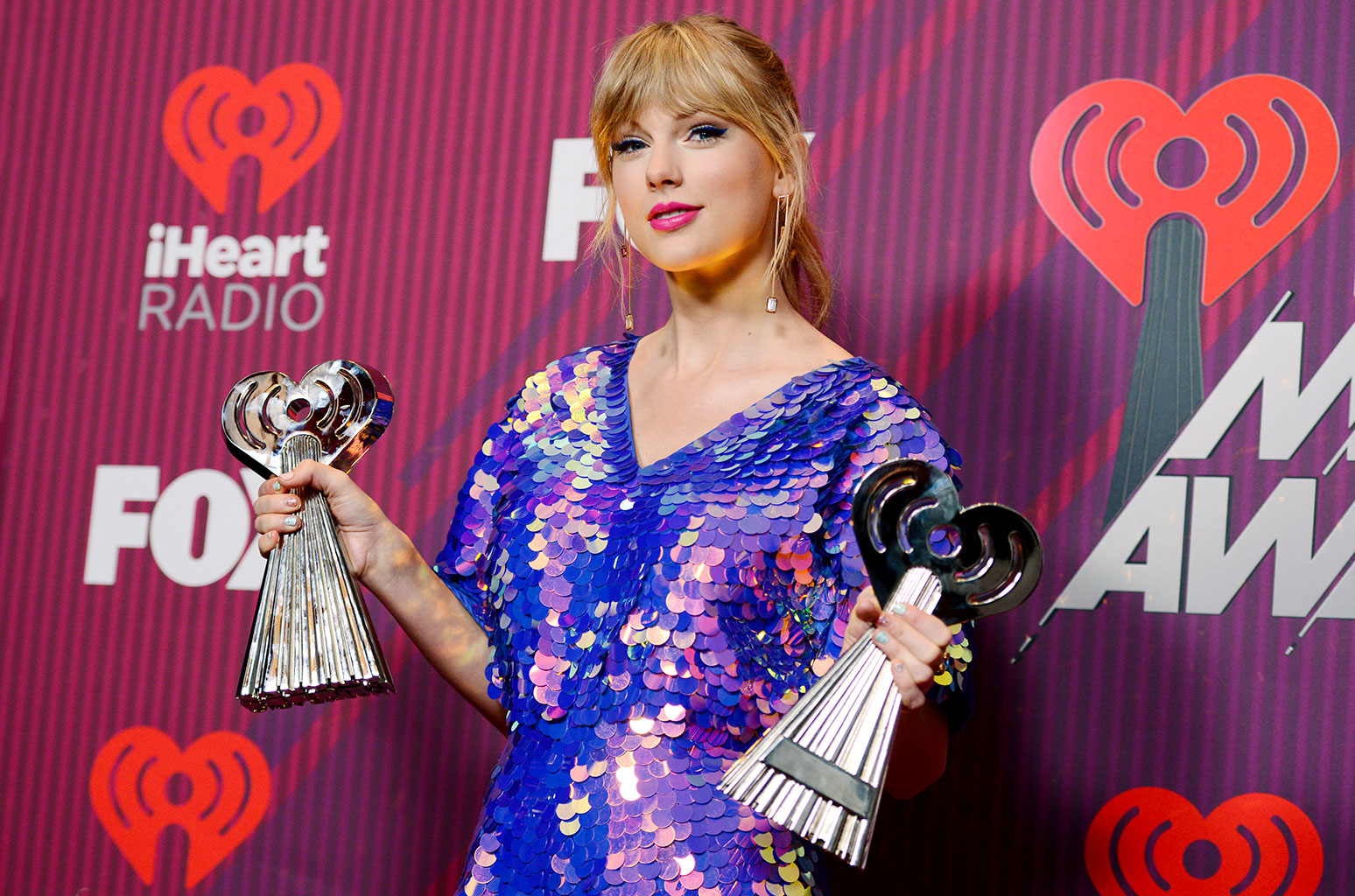 Taylor Swift holding her trophies at the IHeart Radio awards.