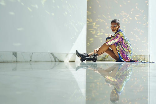 Woman in purple sequin kimono sits in a marble room. 