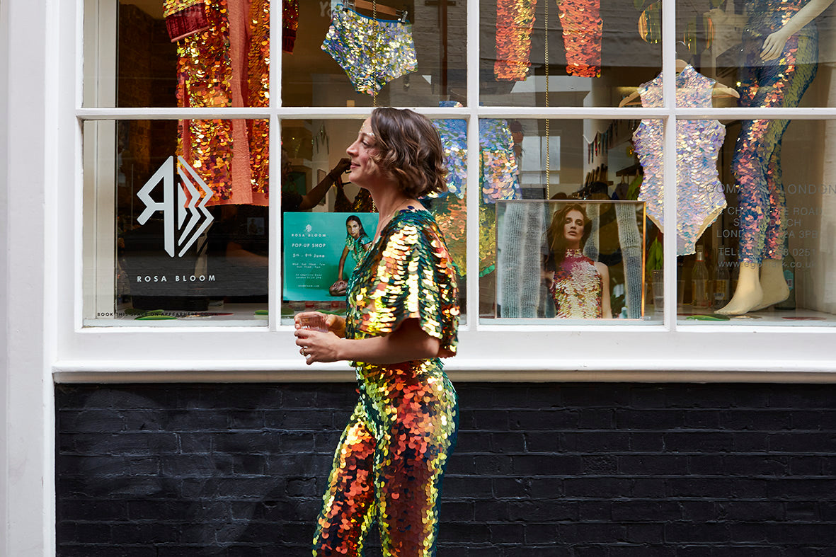 Woman in sequin outfit walks past the Rosa Bloom pop up shop