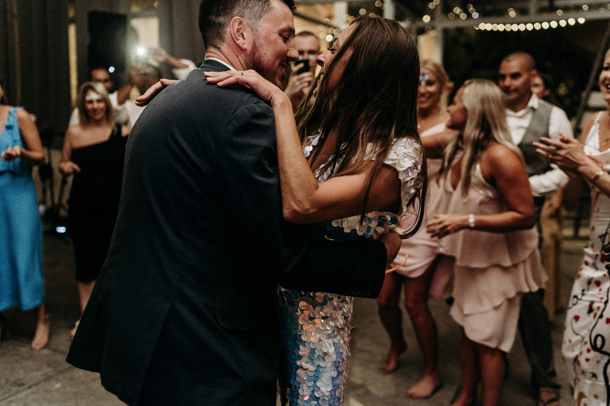 Bride wearing sequin jumpsuit shares first dance with groom