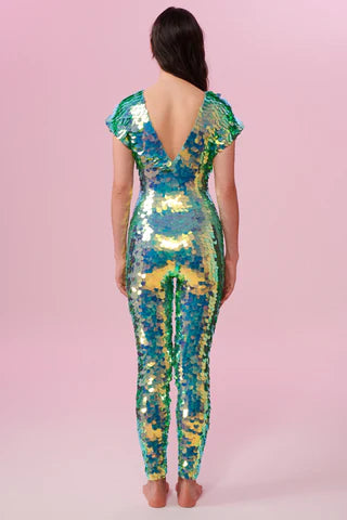 A woman wearing a light green sequin catsuit poses with her back to the camera