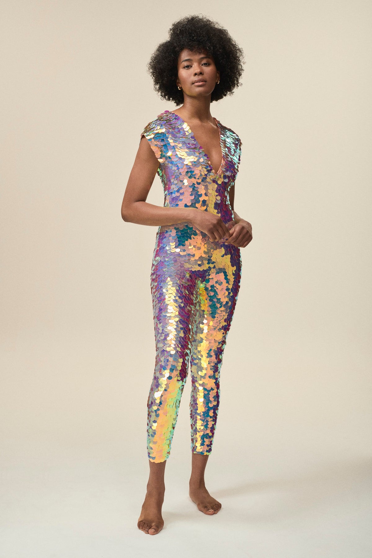 A woman wearing a rose sequin jumpsuit poses for the camera.