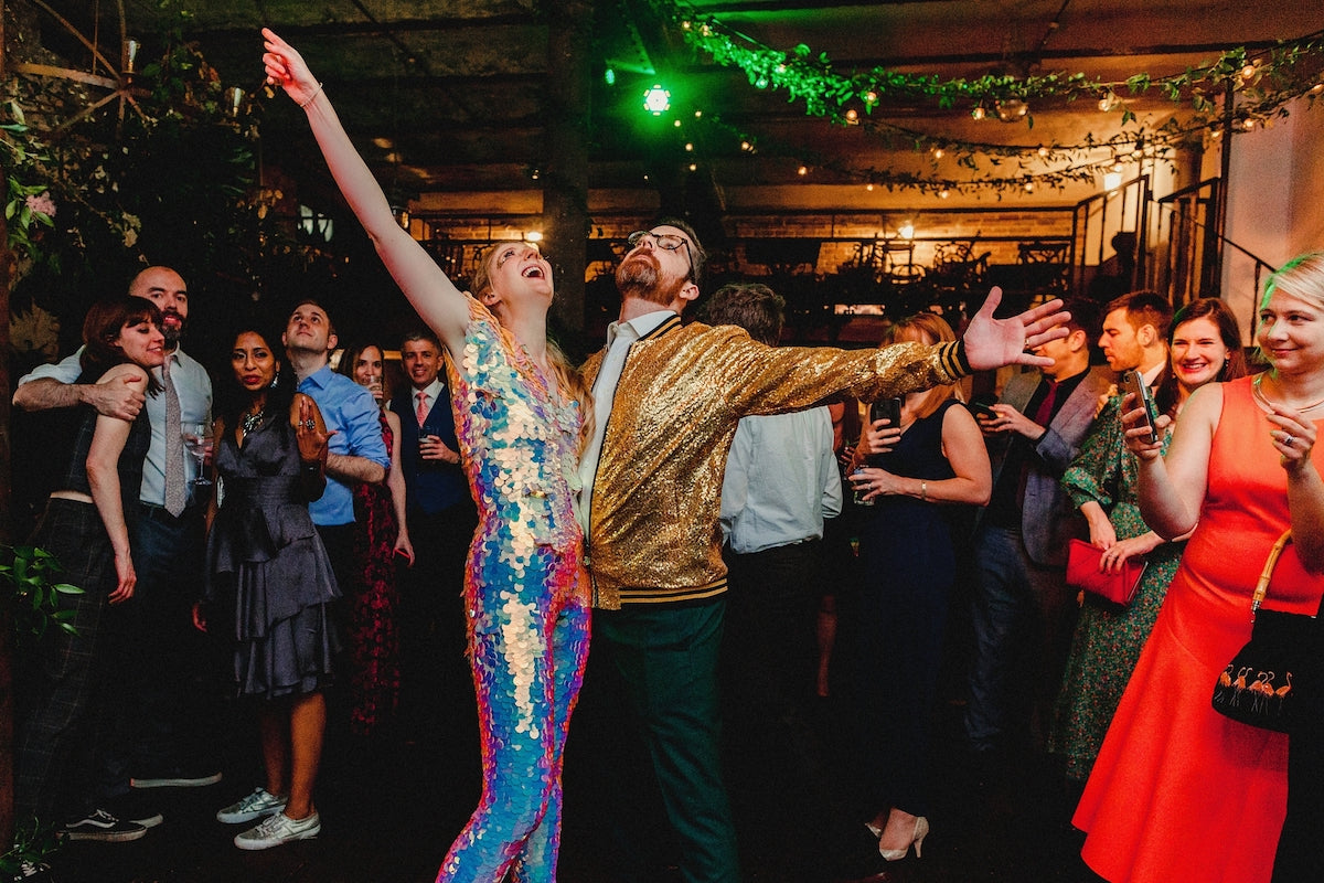 A bride and groom are captured throwing their hands up on the dance floor at their reception. 