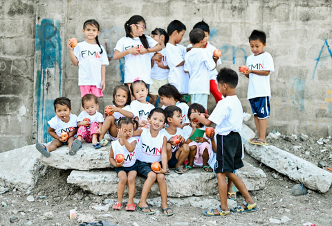 Group of kids wearing FMM shirts and holding food