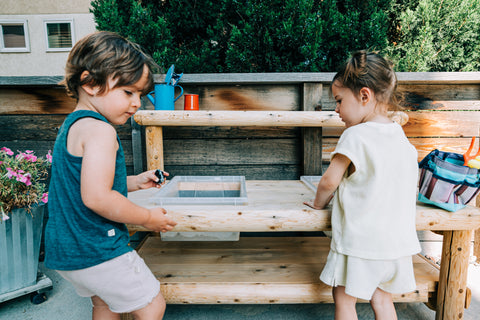 Toddlers playing outside at a water table