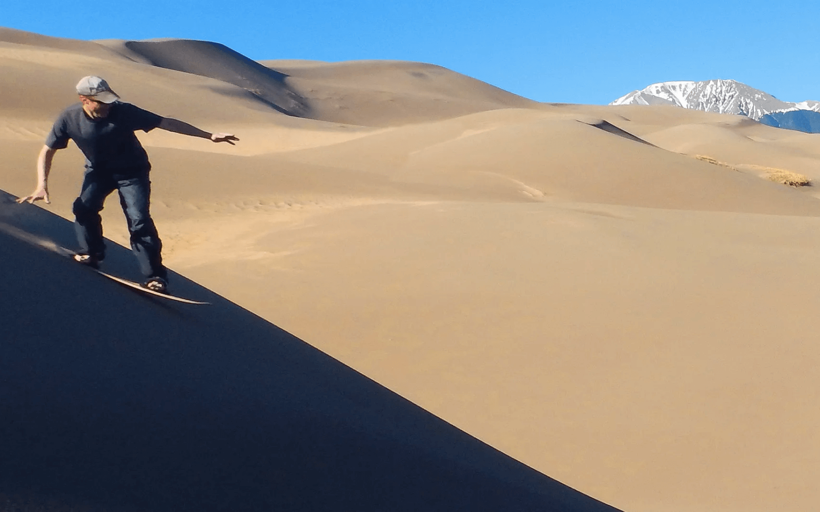 a man surfing down a sand dune 