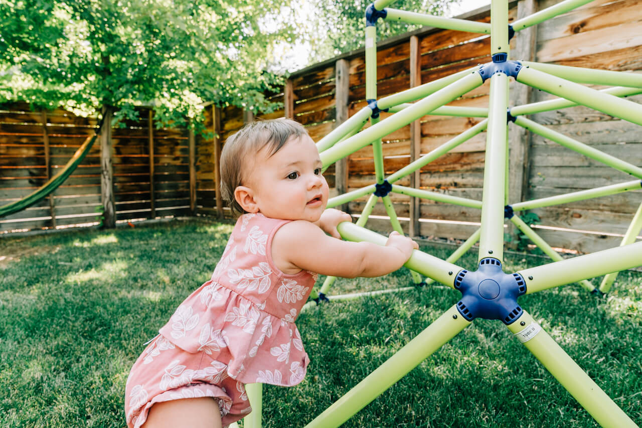 9 month old girl playing outside on jungle gym