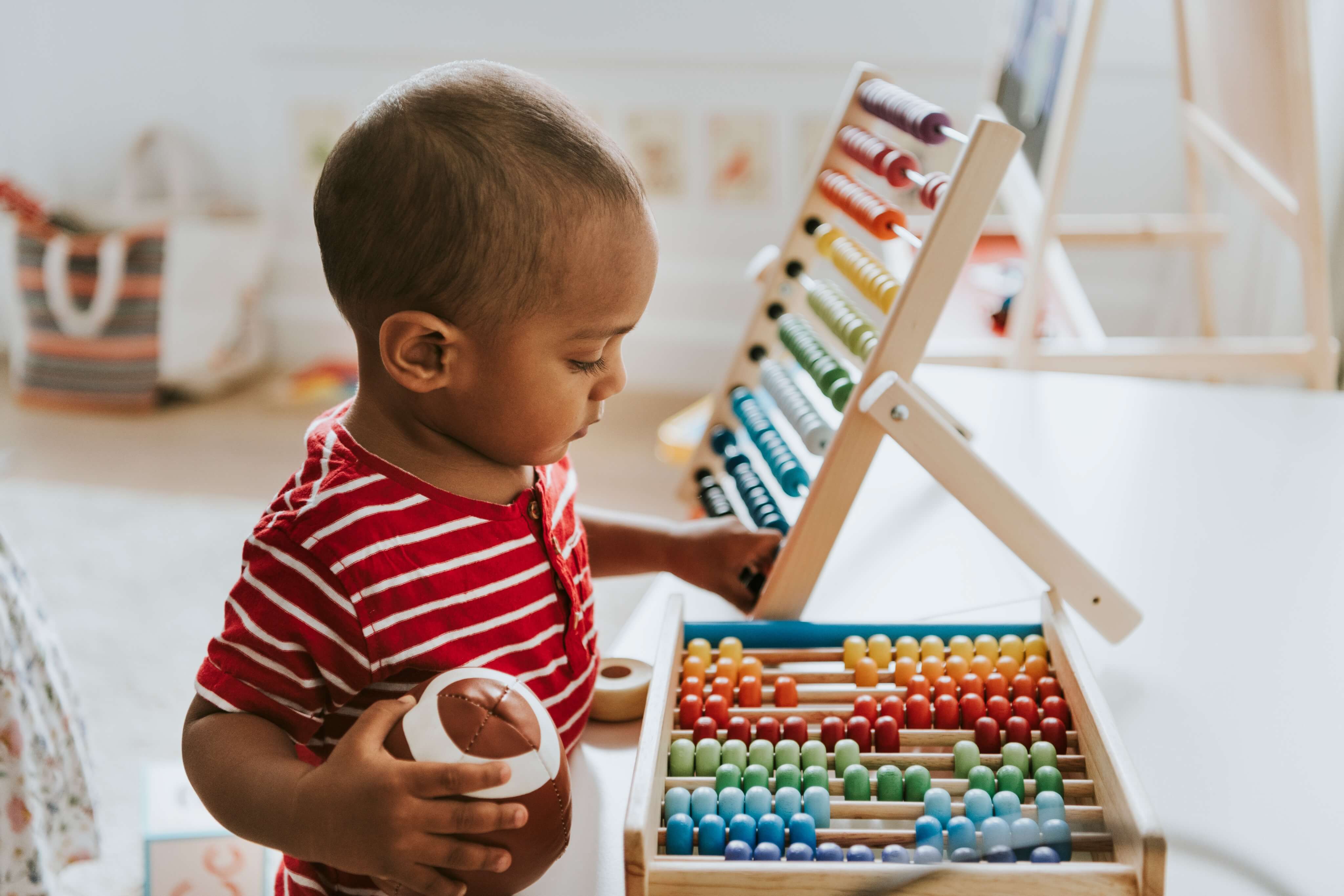 little boy playing with wooden rainbow bead counters