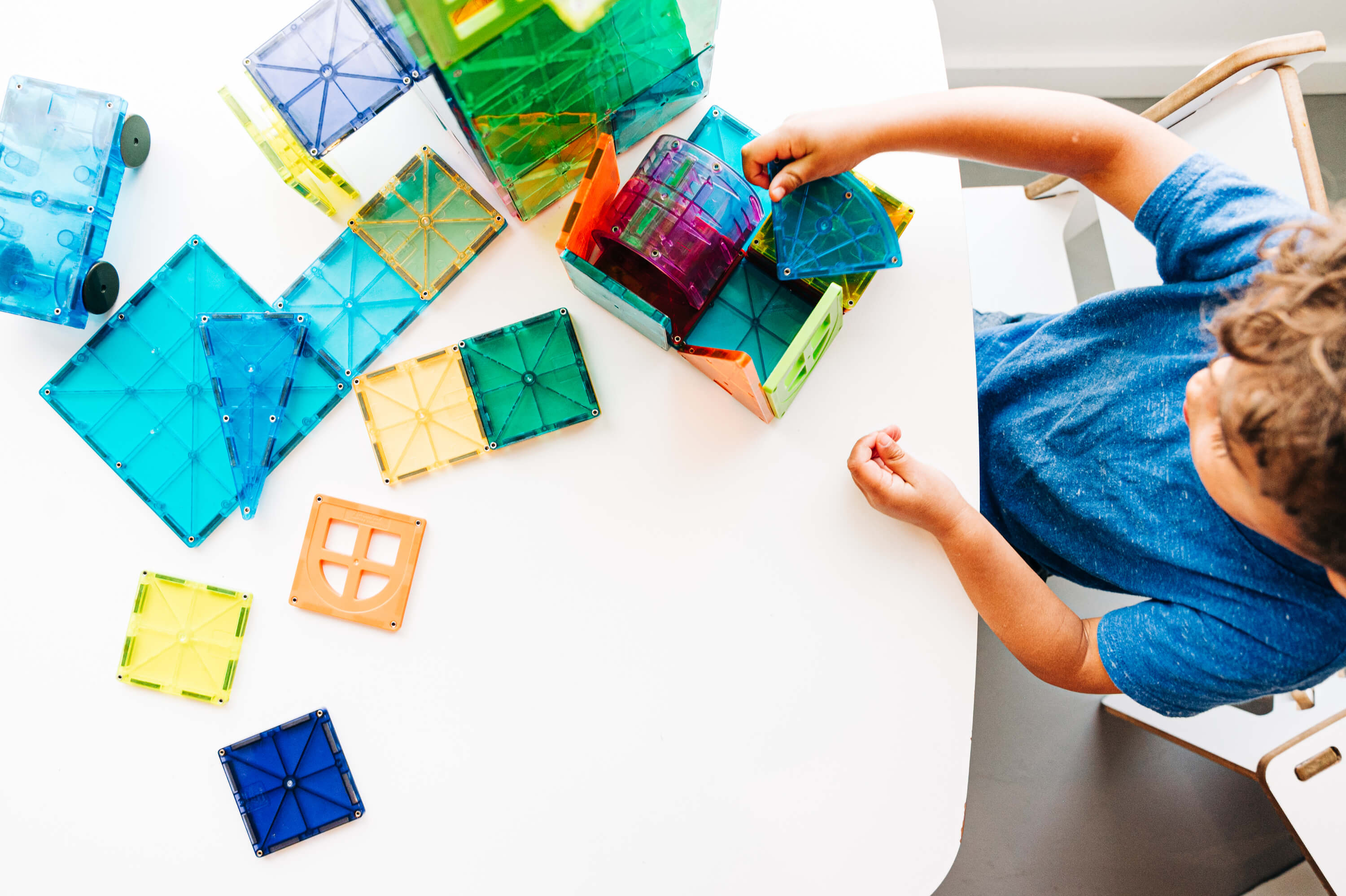 toddler playing with colorful magna tiles inside 