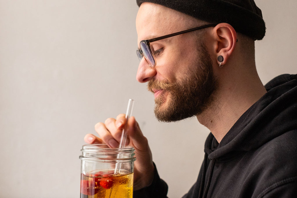 Jan genießt das Glas mit kühlem Zitronenbasilikum-Eistee mit Himbeeren und Ingwer