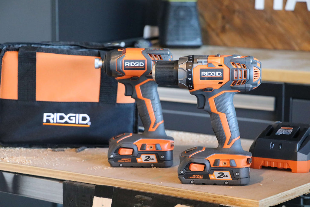 Ridgid 18V Drill/Driver and Impact Driver Combo Kit , RIDGID tool bag and RIDGID charger sitting on a piece of plywood in a wood shop