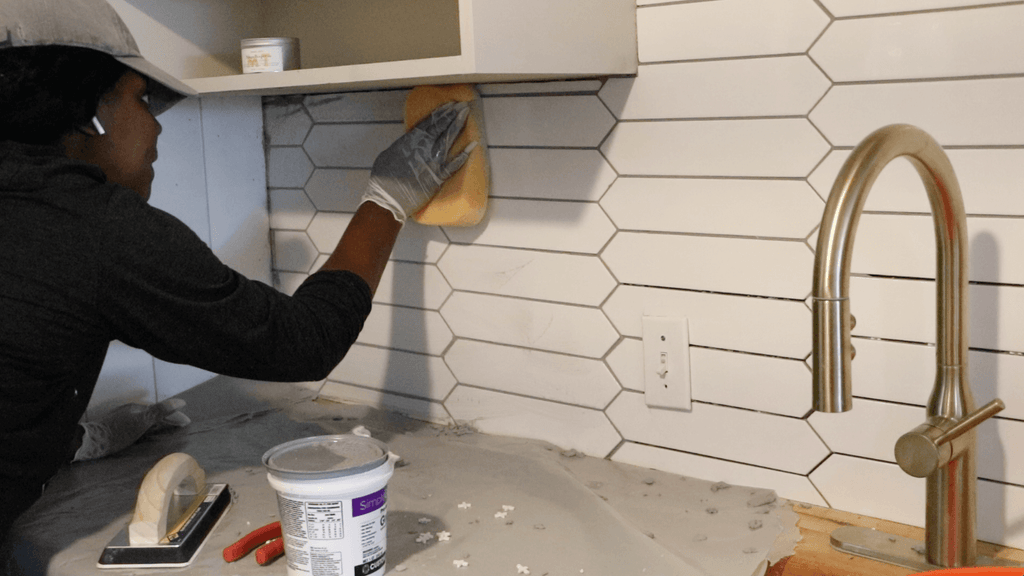 Wiping off excess grout with sponge