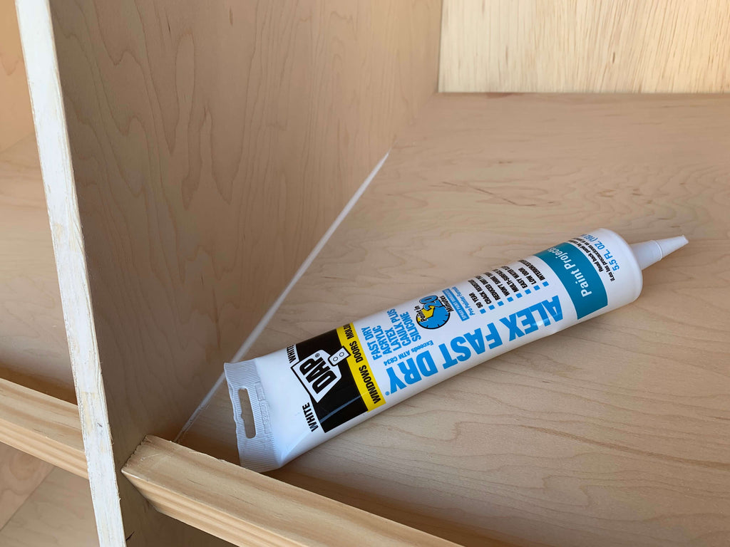 Dap Caulking sitting on a shoe cabinet shelf