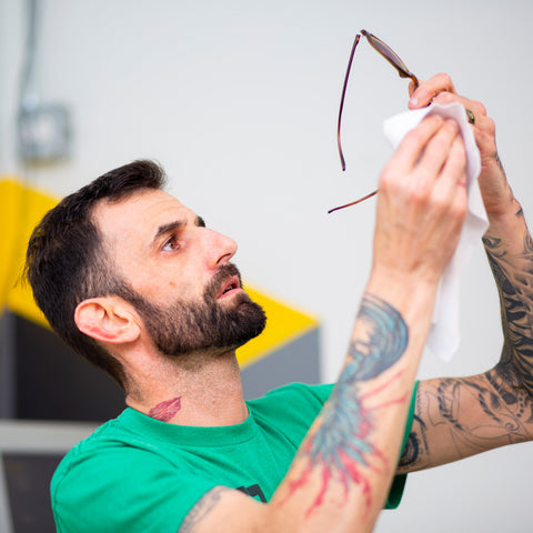 man holding up sunglasses in lens lab