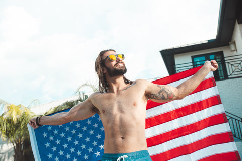 Man wearning sunglasses holding American Flag