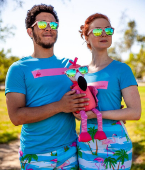 Man and woman are dressed in bright clothes while holding stuffed toy and looking into distance