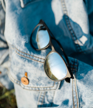 Glasses sit on a denim jacket in the grass