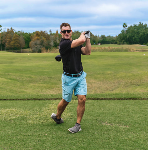 Man swinging a golf club while wearing black Fuse Egmont sunglasses