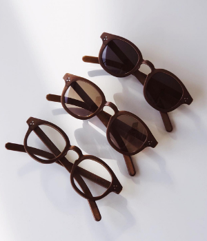 Three brown sunglasses with different lenses are lined up on a white desk