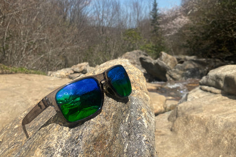 Clear-Grey Fuse Egmont Sunglasses with Sapphire Fuse lenses placed on top of a rock