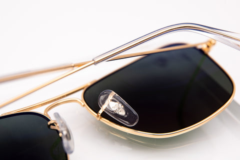 Gold aviator Ray-Ban with dark lenses and a RB engraved under the transparent nose pad