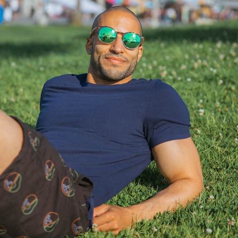 Man wearing round sunglasses laying in the grass