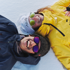 Man and woman laying down with sunglasses in snow