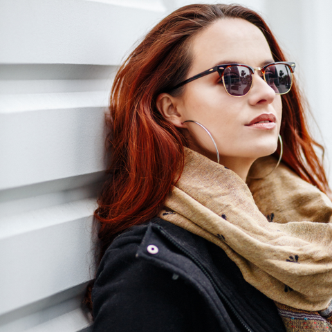 Woman wearing Photochromic lenses laying against a wall.