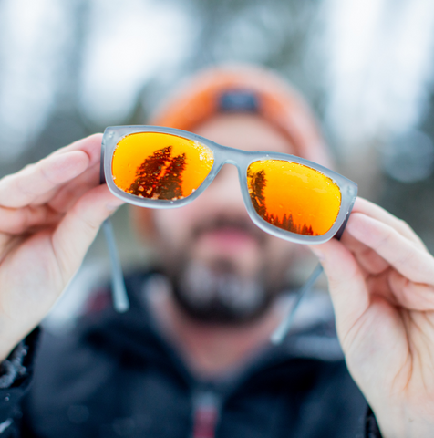 Cascade Orange Sunglasses being held by man in snow