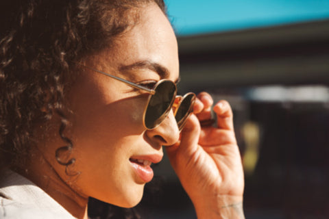 woman holding sunglasses in front of face