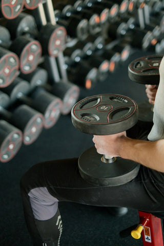 man's arms holding dumbbell weights ready for a set at the gym