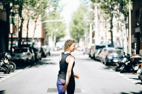 Blonde woman walking in the road with downtown city street in front of her