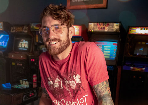 Man smiles in an arcade. His glasses have a light yellow tint