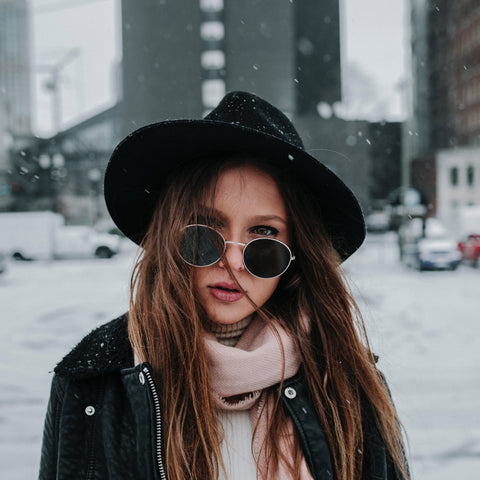 woman in black hat with sunglasses on in the snow