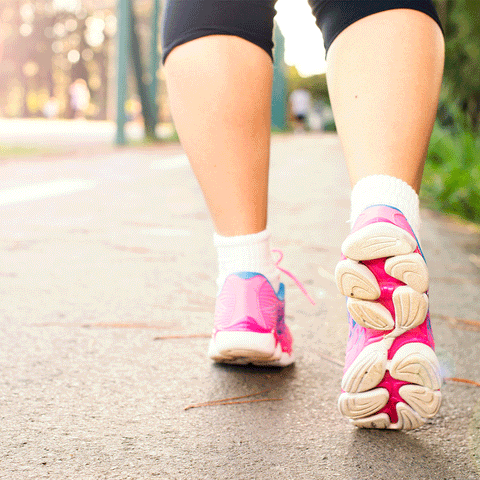 person walking on pavement with pink sneakers